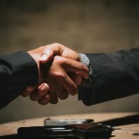 Business owner shaking hands with a PPC advertising agency over a wooden table